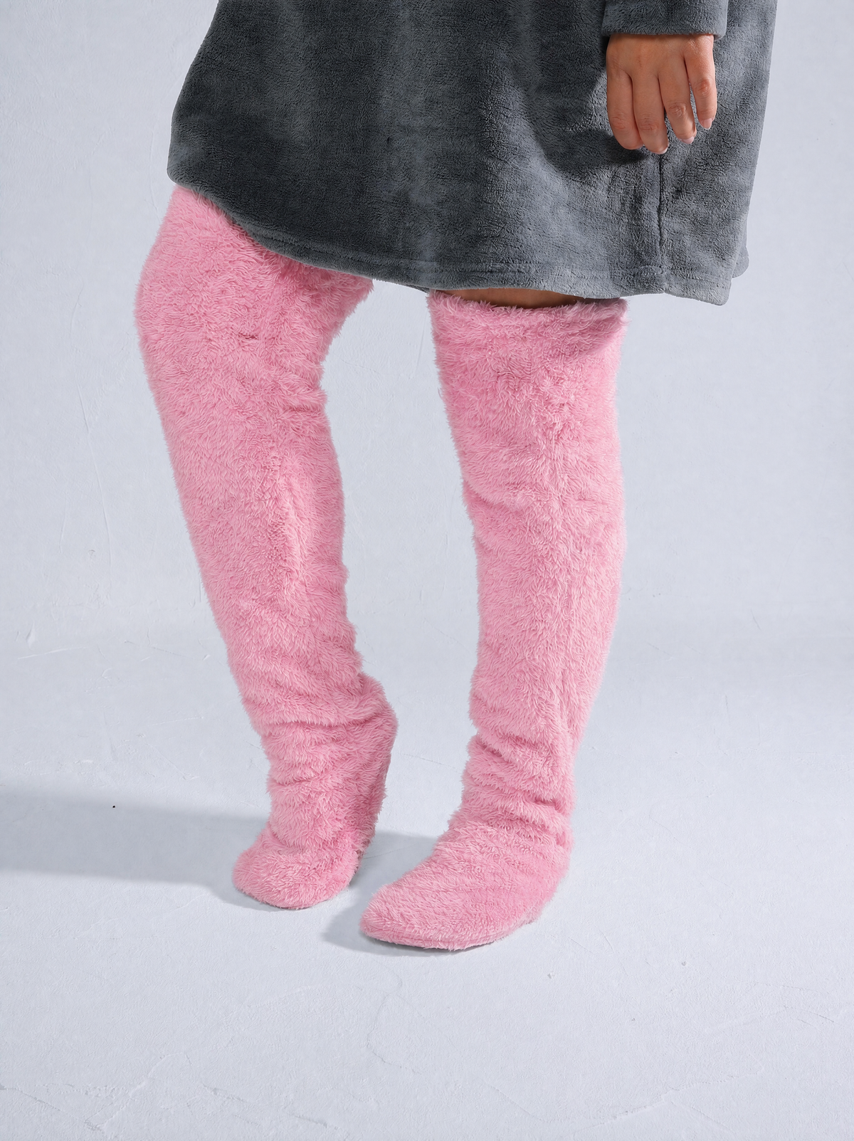 Woman wearing pink fluffy thigh-high socks with a gray oversized sweater
